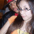 Two figures in close embrace, one with dark hair and red headwear, the other with light-colored hair and glasses, against a blurred background.