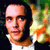 Static pixelated image of a person with dark hair and light skin wearing a white shirt against a blurred background with green, orange, and yellow tones.