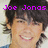 Pixelated image of a smiling person with dark hair, wearing blue clothing against light background.