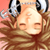 A pixelated close-up of a person with long brown hair wearing large black-and-white headphones, eyes closed in a relaxed expression against a peach background.