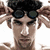 A pixelated image of a person with dark hair and goggles on their head, wearing a black bow tie against a white background.