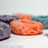 A pixelated orange object resembling a fish or salmon fillet rests on a white surface with a blurred background of blue and gray tones.