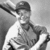 Black-and-white image of a person wearing a cap and striped shirt holding an object, with visible pixelation.