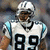 Pixelated image of a football player in a white uniform with black number 89, light blue shoulder accents, and a white helmet, standing against a blurred background.