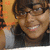 A person with short dark hair and glasses smiles in a of four showing slight head movement against an orange background