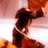 Pixelated figure with dark hair in a high ponytail, wearing a white and brown outfit with red accents, standing against a gradient background of pink, white, and orange hues.