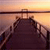 A pixelated static image shows a dark silhouette of a vehicle on a bridge against a sunset sky with orange and yellow gradients.