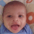 Pixelated close-up of a child's face with short brown hair, wearing a blue collared shirt, against a blurred background with orange and beige tones.