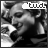 Black-and-white animated icon showing a person with short hair holding a microphone, smiling while text above changes from 'tud' to 'udl'.
