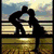 Silhouette of two figures kissing on a bench with a sunset sky, heart-shaped hands, heart drawn in sand, ring box with rings, and a heart drawn with a pen.