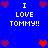 Blue background with pixelated text "I LOVE TOMMY!!" and heart symbols in red/purple, arranged in a pattern