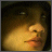 A pixelated close-up of a person's face with warm yellow and orange tones, dark hair visible on the left side, and subtle facial features including eyes and lips.