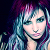 A static close-up of a person with multicolored hair featuring purple, blue, and pink tones, styled with bangs and long waves, against a dark background.