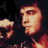 Pixelated static image of a stylized male face with warm tones and dark background, likely representing a celebrity or cultural figure in low-resolution digital art style.