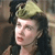 A pixelated close-up of a person with dark hair wearing a light-colored headpiece, set against a blurred background.