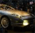 Pixelated image of a car with headlights on, positioned on a dark background with a light streak across the top.