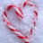 A heart-shaped candy cane arrangement on snow with red text reading 'let it snow<3' on a white background.