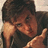 A person with brown hair in a dark shirt rests their head on one hand, making a peace sign with the other hand against a light background.