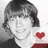 Pixelated grayscale portrait of a person with short dark hair and bangs, holding a red heart-shaped object against a light background.