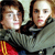 Two people in a close-up pose with one person's arm around the other's shoulder, wearing dark and light gray clothing with red and yellow accents.