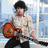 Six pixelated show a person with dark curly hair in various poses: playing guitar, adjusting sunglasses, leaning on a desk, covering mouth, singing into microphone, and seated at piano
