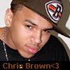 A person wearing a dark cap with a shield-shaped patch featuring a stylized face and red-green-yellow stripes, a dark shirt, and a silver chain necklace, with text at the bottom reading "Chris Brown<3".