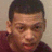 Pixelated close-up of a person with short dark hair wearing a maroon top against a light beige background.