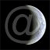 A circular grayscale icon with a stylized @ symbol at its center, rendered with pixelated edges against a solid black background.