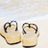 Two beige flip-flops on light sand with a pale sky background, next to bright pink text reading "wish u were here" in blue pixelated letters.