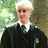 A pixelated image of a person with short blonde hair in a dark robe, set against a bright pink background with cyan text.