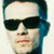 Static pixelated icon of a person wearing dark sunglasses with blue hair, cropped to show only the upper face and head against a light background.
