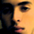 Pixelated close-up of a person's face showing right eye, nose, and mouth with warm yellow-orange lighting and dark background.