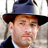 Static 48x48 pixel icon of a person wearing a dark blue fedora with black brim, light brown hair visible beneath the hat, and a white collared shirt under a dark jacket.