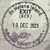 Circular grayscale stamp with text and map elements, pixelated appearance on light background.