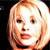 Static pixelated image of a person's face with light brown hair and visible facial features against a dark background.