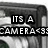 Black-and-white animated icon showing a camera lens with text "ITS A CAMERA<3" that changes to "ITS A CAMERA<3S" across frames.