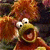 A 50x50 pixel animated buddy icon featuring a cartoon character with brown fur and yellow face on the left, next to green text reading "Original Icons .com" on a dark background.
