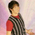 Pixelated image of a person with short dark hair wearing a red shirt and black-and-white checkered vest against a soft pink and white background.