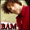 A person with brown curly hair wearing a red collared shirt, with large red text reading "BAM" at the bottom of the image.