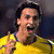 A person in a yellow sports jersey with blue trim makes a celebratory gesture, mouth open wide as if shouting or cheering.