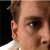 Pixelated close-up of a person's face showing ear, eye, and part of nose with light skin tone and dark hair against dark background.