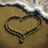 A beach scene with a heart drawn in sand, green text narrating a story about hearing 'I love you' from the waves.