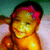 Pixelated image of a person with dark hair, red and purple headband, closed eyes, and warm-toned skin against a teal and pink background.