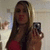 A pixelated image of a person with long dark hair holding a camera, wearing red clothing against a light background.
