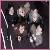 Pixelated image of multiple figures in dark clothing with light skin tones against a dark background, featuring vertical white lines on the left side.