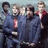 Group of six people in dark blue uniforms with red accents posing together, one person's face blurred.
