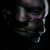 Pixelated dark-toned image with indistinct shapes and muted colors, showing partial forms against a black background.