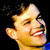 Pixelated close-up of a person's face with closed eyes and mouth open in laughter, set against black background.