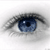 Pixelated close-up of a human eye with blue iris, black pupil, and dark eyelashes against a light gray background.