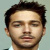 Pixelated static image of a male face with dark hair and light skin, cropped to show head and upper neck against a plain background.